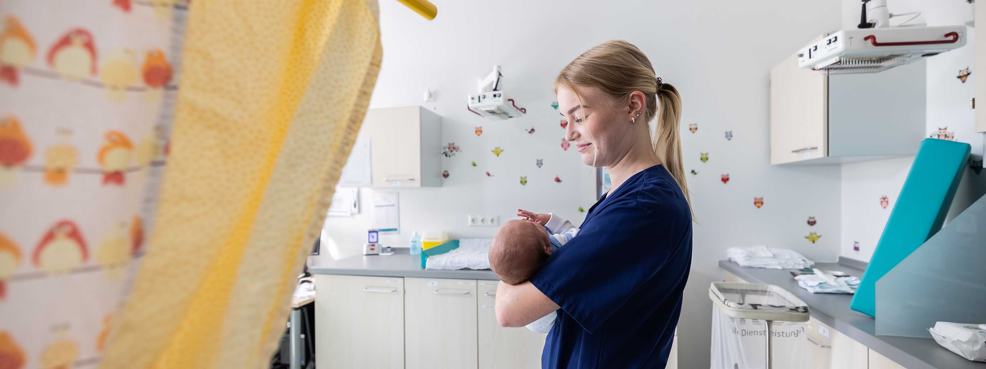 Eine Mitarbeitende hält ein Baby